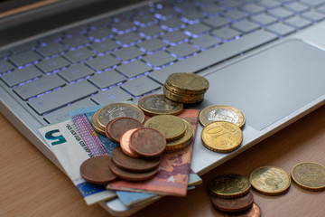 Grupos de monedas y billetes encima de un ordenador 