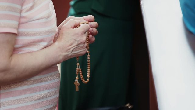 In old, elderly, wrinkled caucasian hands, a woman holds Catholic beads, rosary and sorted them out