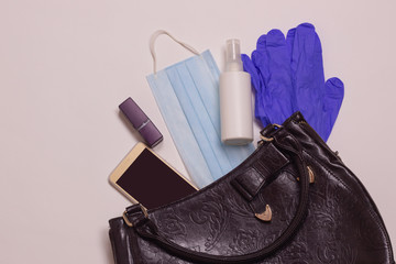 Coronavirus protection. Medical mask, disinfecting gel and gloves in a women's bag.