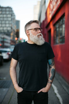 Fashionable, smiling bearded man hanging out downtown alone