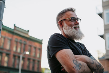 Fashionable, smiling bearded man hanging out downtown alone