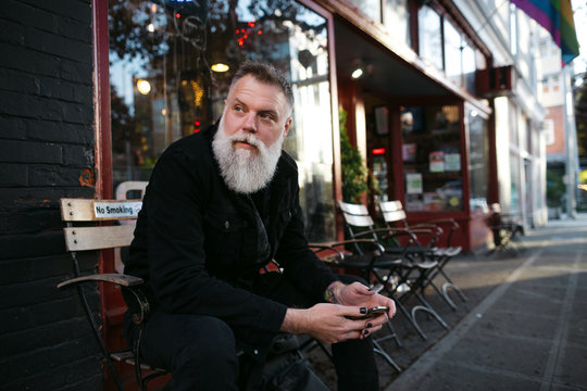 Fashionable bearded man hanging out in the city using is mobile