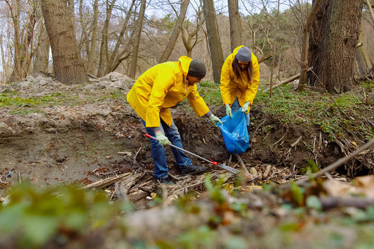 Man getting garbage with rake while woman holding garbage