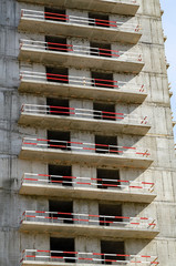 A panel building under construction and security fencing on the balconies.