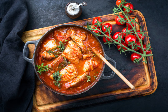 Traditioneller brasilianischer Fisch Moqueca Baiana mit Fischfilet in Tomaten Sauce als Draufsicht in einem Modern Design Gu&szlig;topf