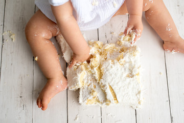 Obraz na płótnie Canvas First birthday cake smash close up details, baby covered in white coconut cake. close up images of the mess. 