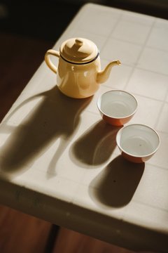 High Angle View Of Teapot And Empty Cups On Table