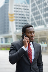 Young handsome African businessman talking on mobile phone