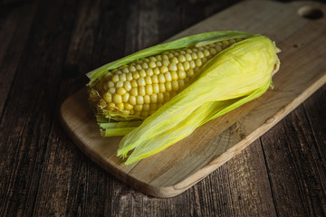 Corn on the cob on a wooden table. Sweet steamed corn on cutting board.
