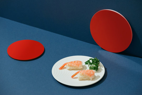 Shrimp sushi nigiri on dish over blue.