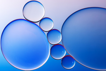 Macro photography of small drops of oil floating on water with blue background. Abstract composition of great beauty. Background for design.