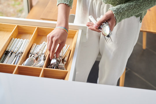 Female taking metallic spoons and forks in box.