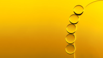 Macro photography of small drops of oil floating on water with yellow background. Abstract composition of great beauty. Background for design.