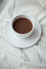 A cup of hot cocoa on the bed. Cozy. Homeliness.