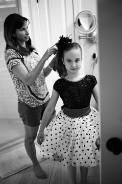 Mother helping cute young girl getting ready for a dance performance