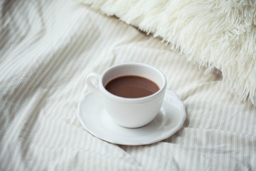 A cup of hot cocoa on the bed. Cozy. Homeliness.