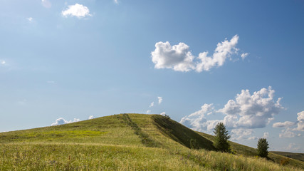 Fototapeta premium top of a green hill against a blue sky with rare clouds