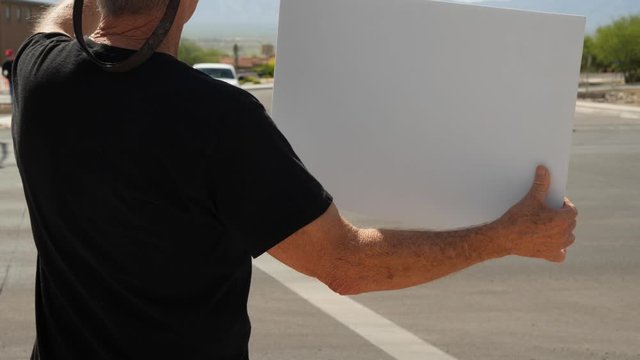 A man holding a sign in protest at a street corner