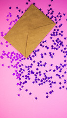 Beautiful craft envelope with shiny blue confetti stars on a pink background. Festive background for women's days and Valentine's day.