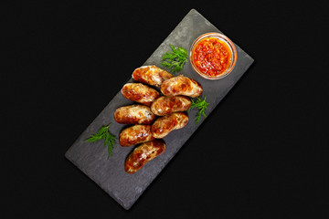 Grilled sausages with sauce on a black background