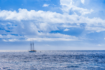 Sailboat on the horizon on a day with dramatic clouds on the Amalfi coast of the Italian riviera