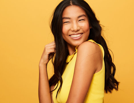 Asian Woman fun portrait Smiling isolated over Yellow Studio Background