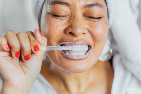 Close Up Of Woman Brushing Her Teeth At Home