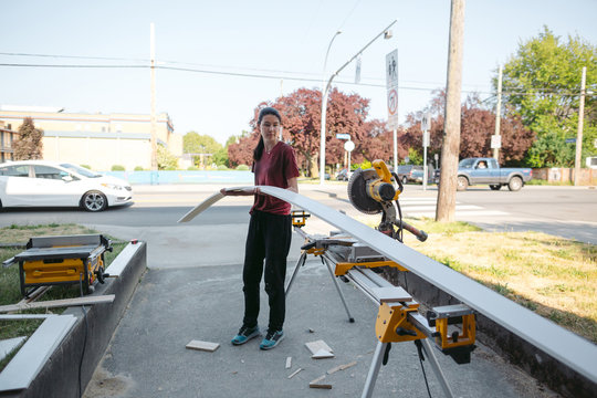 Young woman using chop saw to cut baseboard trim