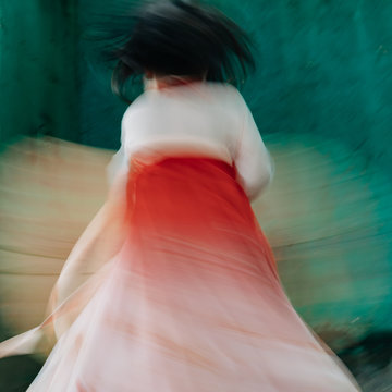 Blurred motion of girl in traditional clothing twirling outdoors