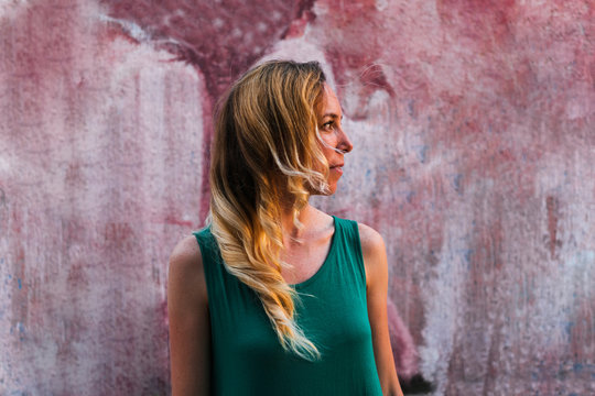 Woman looking at sunset near colorful wall