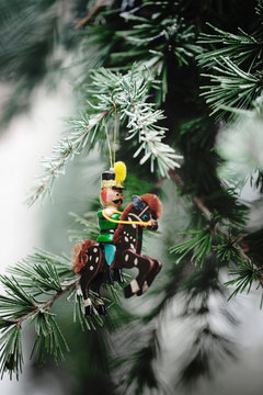 Old fashioned wooden christmad ornament in the shape of a soldier riding his horse hanging from spruce tree in garden