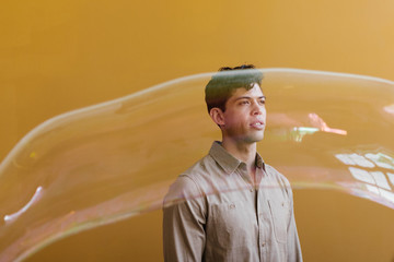 young man with gold background and long bubble in front of face