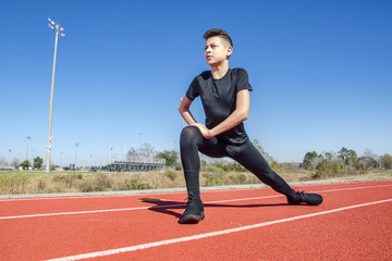 Male child track runner stretching before a race