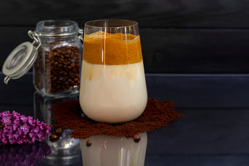 Dalgona coffee is a trendy cold Korean drink. Tasty, aromatic coffee with milk and sugar in a glass on a black background. Copy space