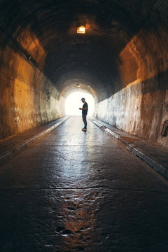 Silhouette of man addicted to the phone in a dark tunnel