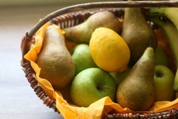 Basket with bananas, apples, pears and lemons. Selective focus.