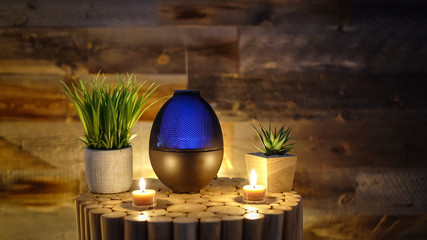 Electric oil diffuser lamp, candles on wooden table in room.