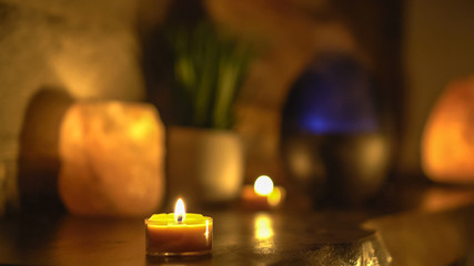 Close-up of burning tealight candle on table in home.
