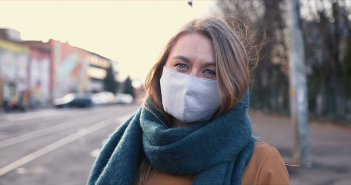 Epidemic control. Portrait of young blonde Caucasian woman wearing safety mask on face outdoors on COVID-19 quarantine.