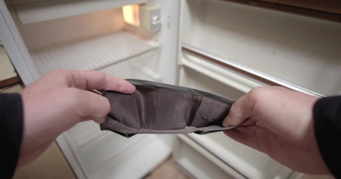 Empty wallet in male hands, empty refrigerator in background, no money for food, economic crisis