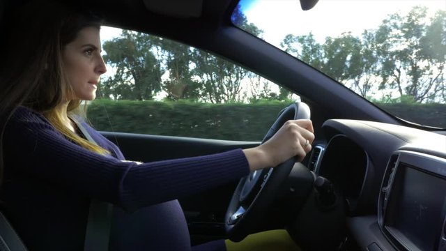 Pregnant woman driving car starting to feel contractions because of bumpy road