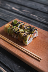 Sushi with salmon on a wooden board on a dark wooden background