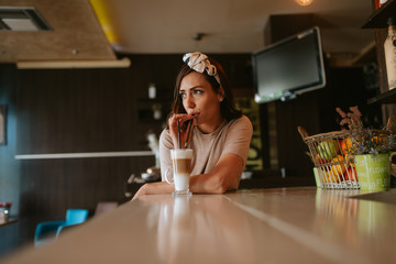 Attractive young caucasian woman drinking a cup of coffee at a bar in a cafe