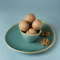 Walnuts in small turquoise ceramic bowl on plate