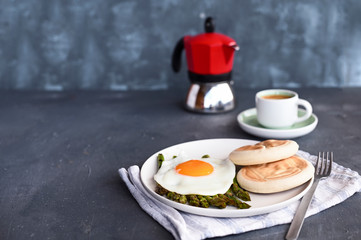 Healthy breakfast. Fried eggs, asparagus, bread and aromatic coffee on a gray background. Free place for text. Soft focus.