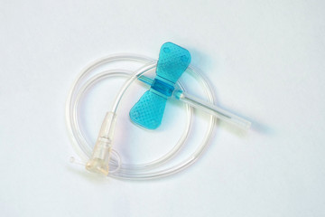 Blue butterfly catheter on light background.  Butterfly dropper needle