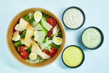 Salad with chicken, cherry tomatoes, lettuce, quail eggs, parmesan cheese, white bread crackers in a cardboard box