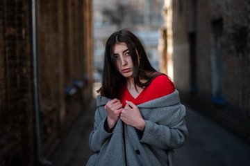 Fototapeta premium Girl in a red blouse and a gray cardigan on the background of the old brick wall