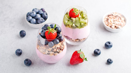 Chia seeds pudding with granola, blueberry and strawberry in glasses. Yogurt with chia seeds, berries, kiwi and muesli for healthy breakfast, copy space