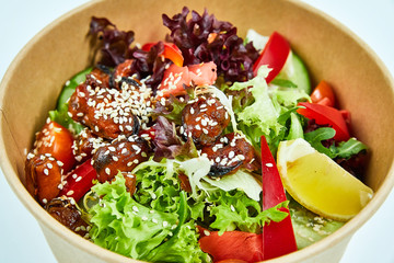 Salad with mussels and cherry tomatoes, red pepper, cucumber, lettuce, ginger, with a slice of lemon, decorated with sesame seeds in a cardboard box